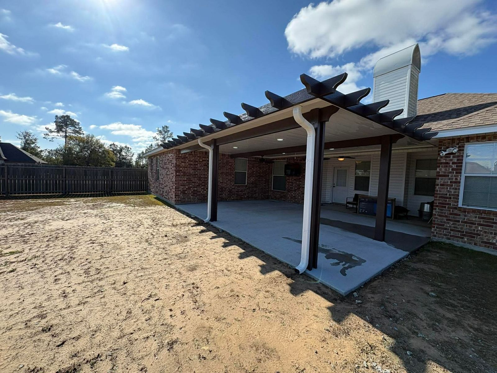 Brown pergola-style patio cover on a brick home
