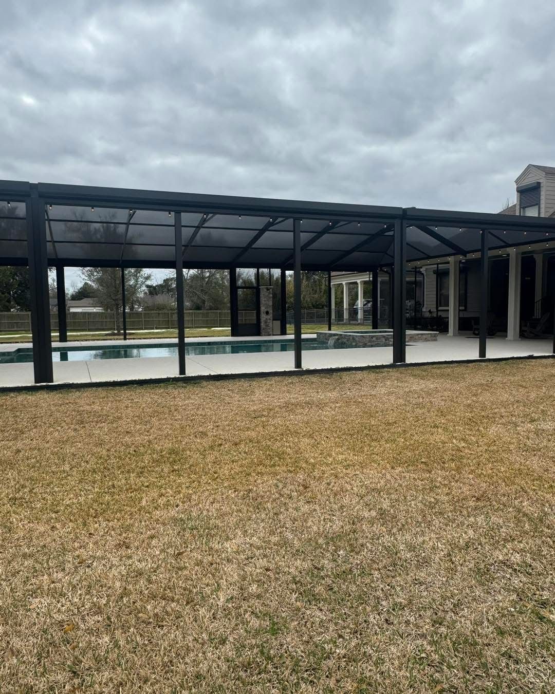 Black-framed pavilion cover over a pool, side view