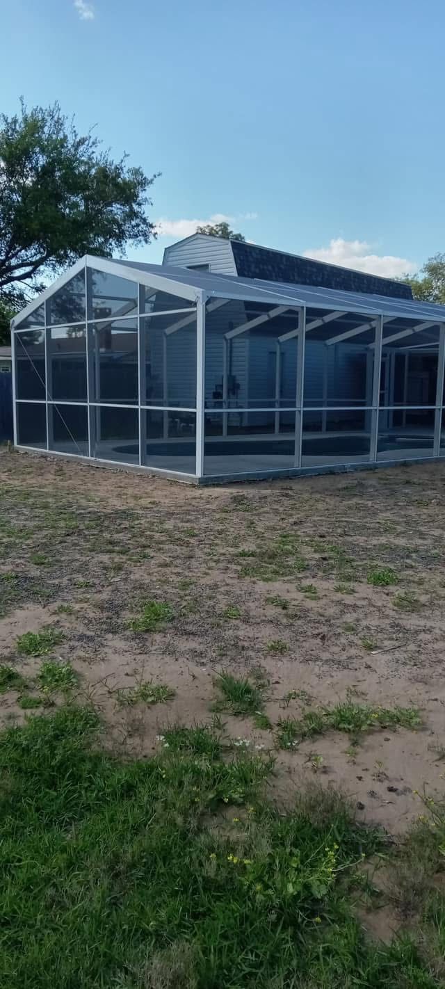 White-framed pool screen enclosure across a grassy back yard