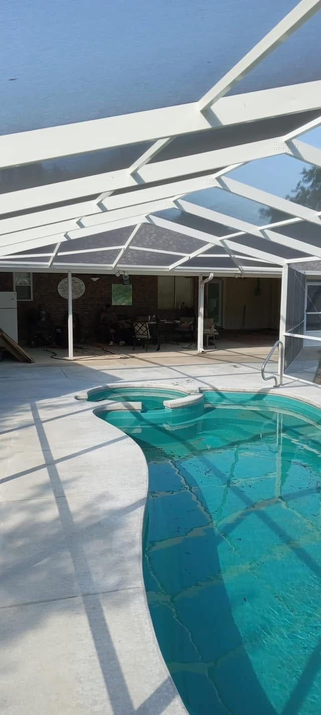 White pool enclosure frame over a curved pool, interior view