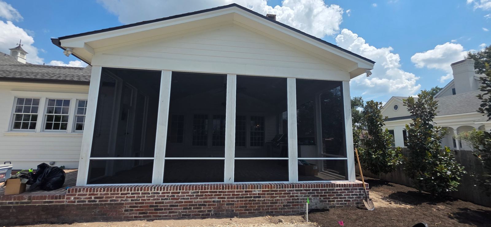 Screened-in back porch with black aluminum framing on a brick base