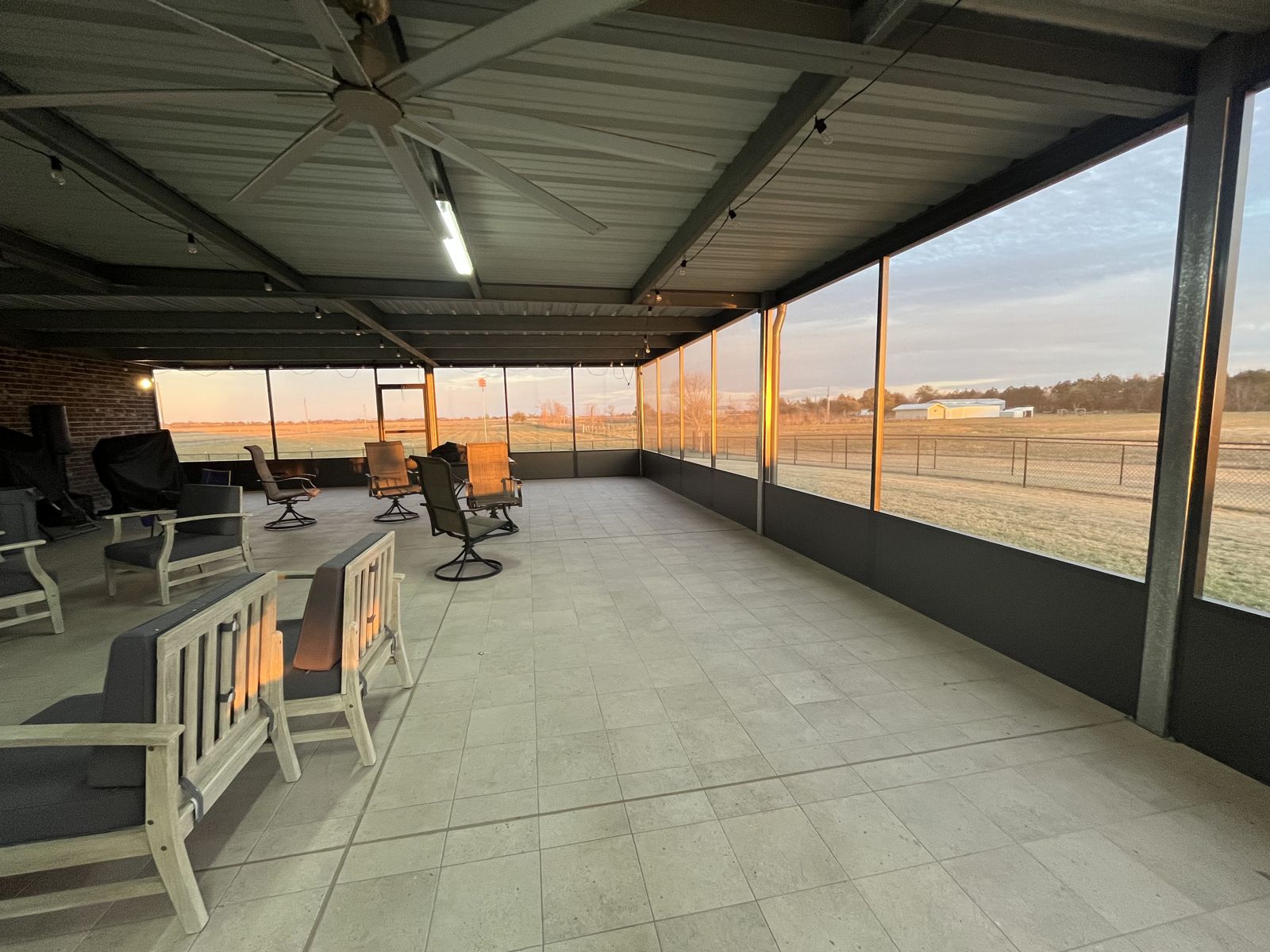Inside a large screened porch under a metal roof with ceiling fans