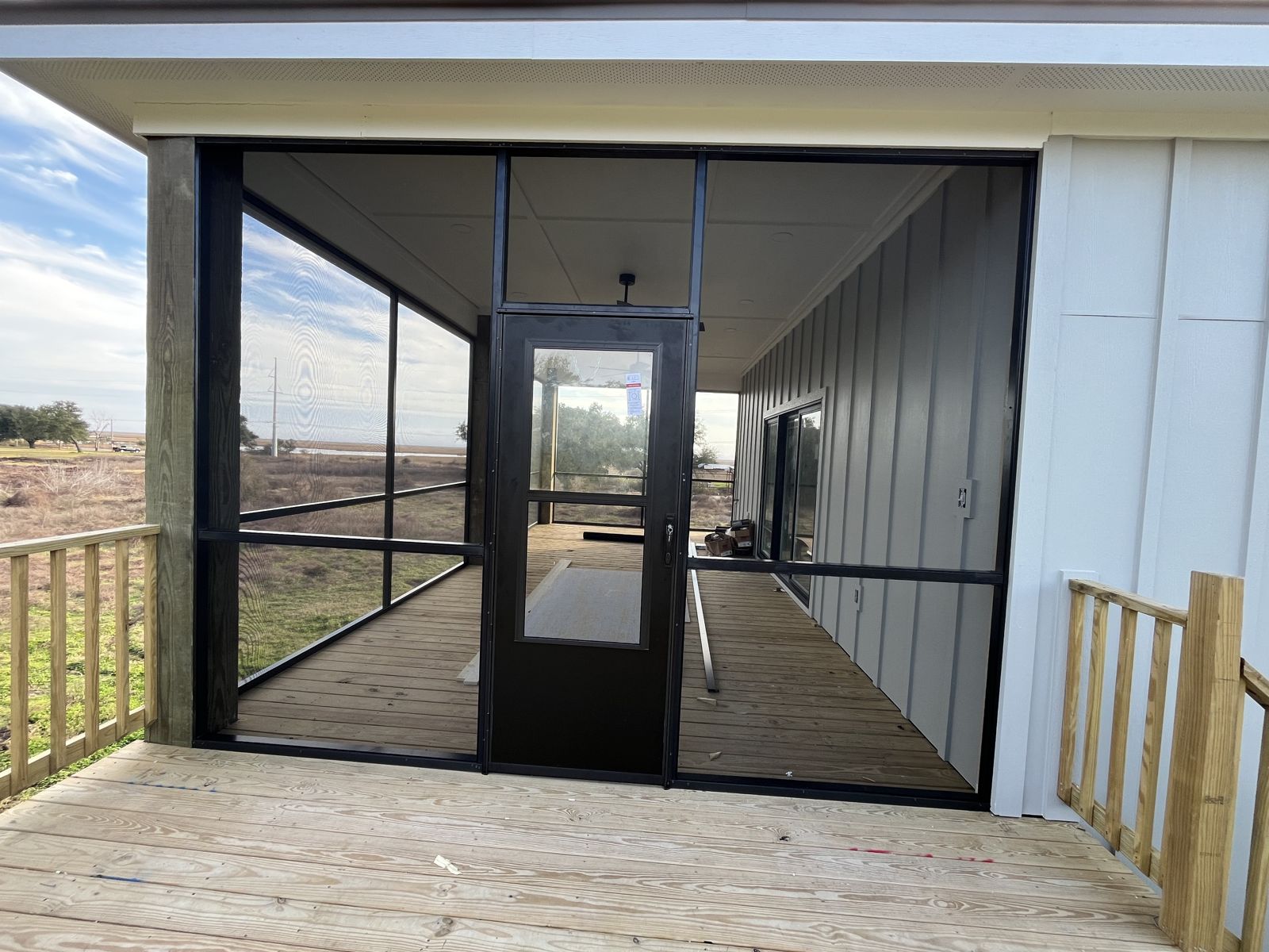 Elevated screened porch with black screen door on a wood deck