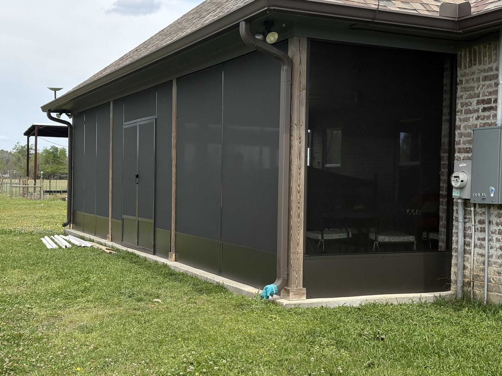 Dark bronze screen room with double screen doors on a brick home