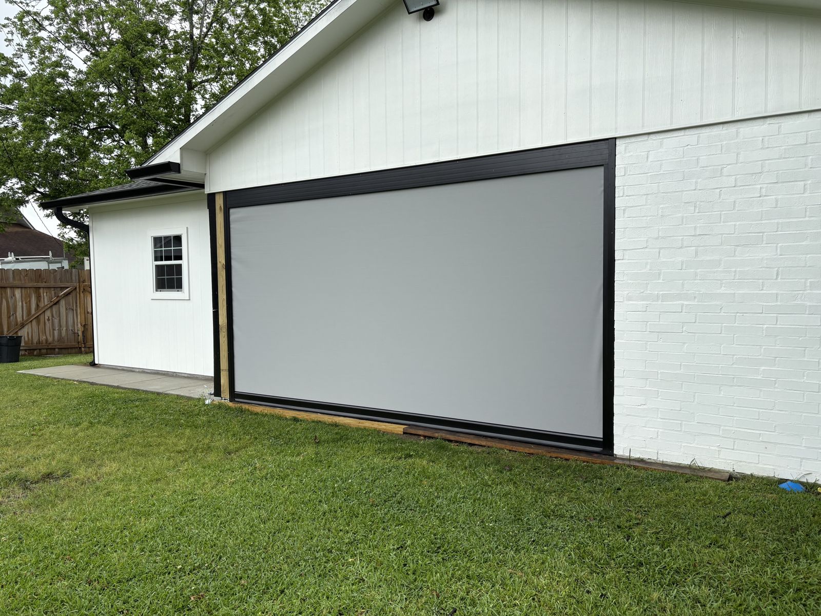 Gray motorized shade lowered on a white home covered patio
