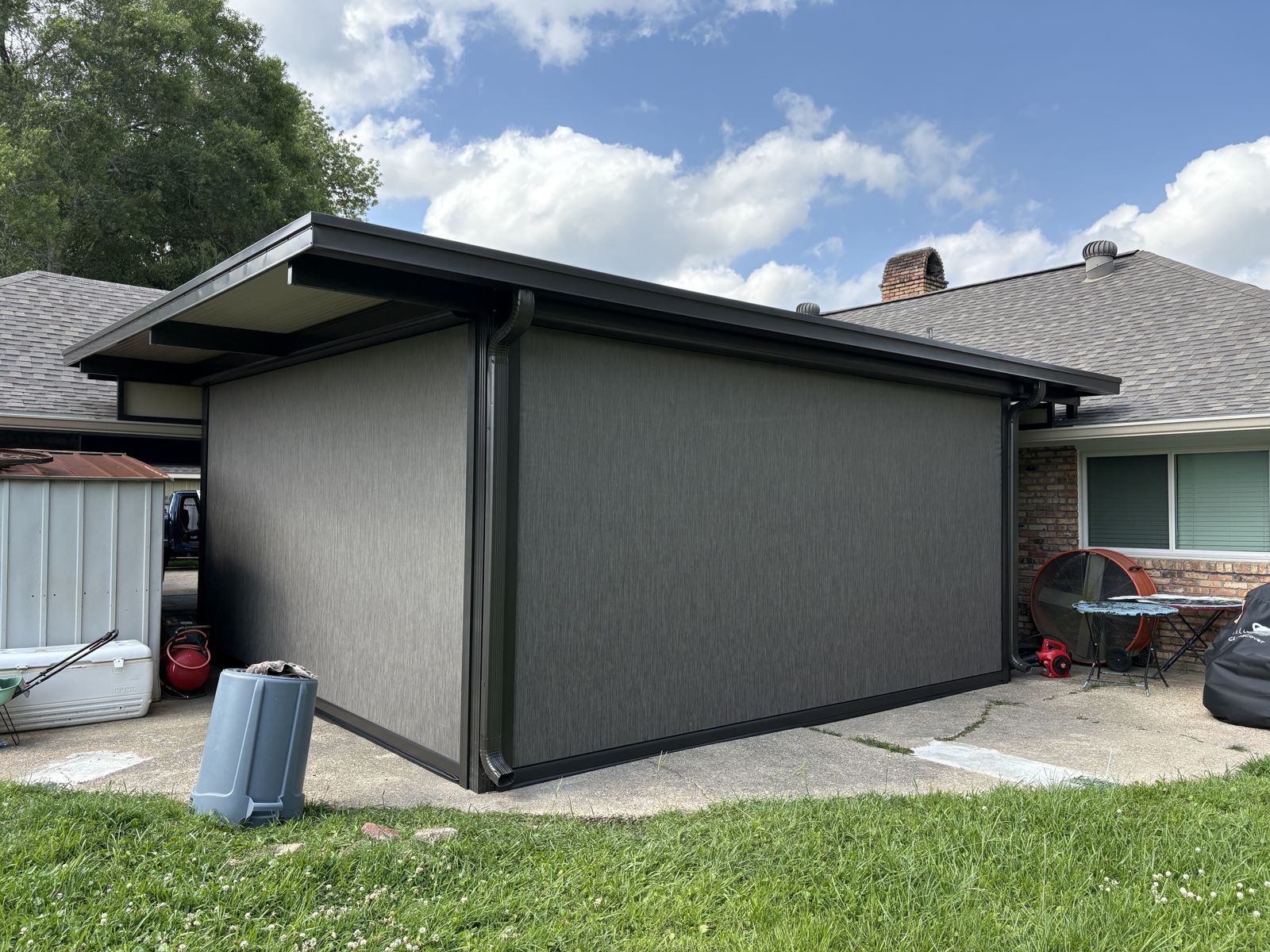 Dark gray motorized shades enclosing a backyard patio cover