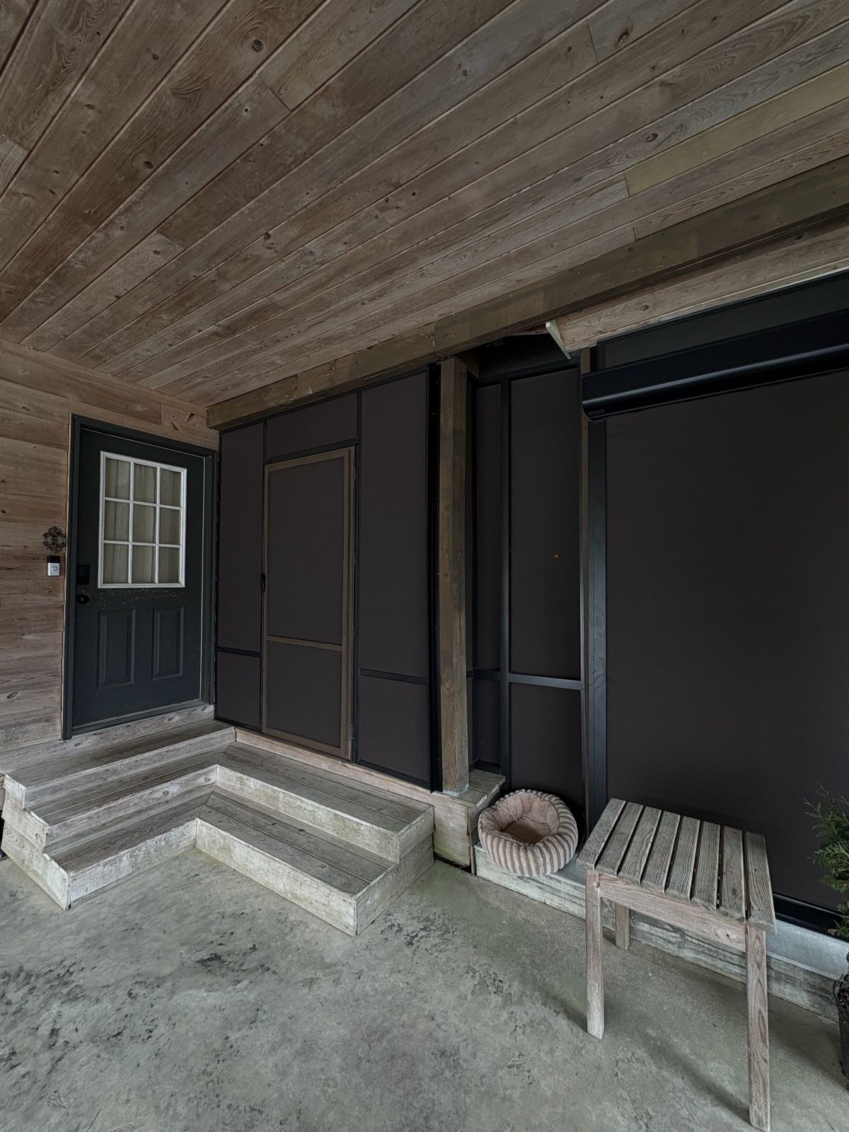 Brown shade panels beside a wood door on a covered porch
